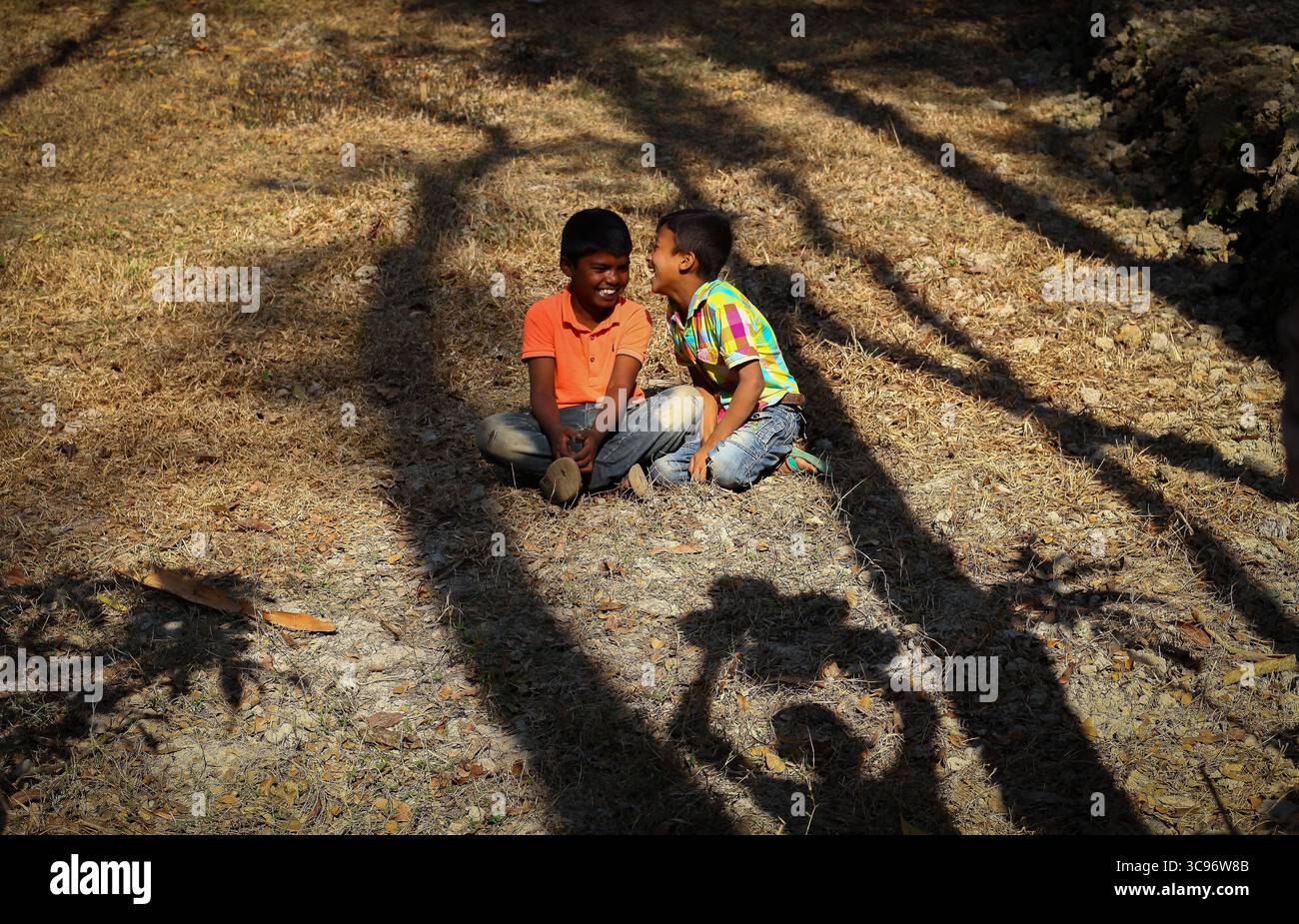 Chattogram, Bangladesh - 12 gennaio 2019: Vista di due ragazzi in abbigliamento casual, che condividono storie tra la luce del sole e le ombre sul gras secco Foto Stock