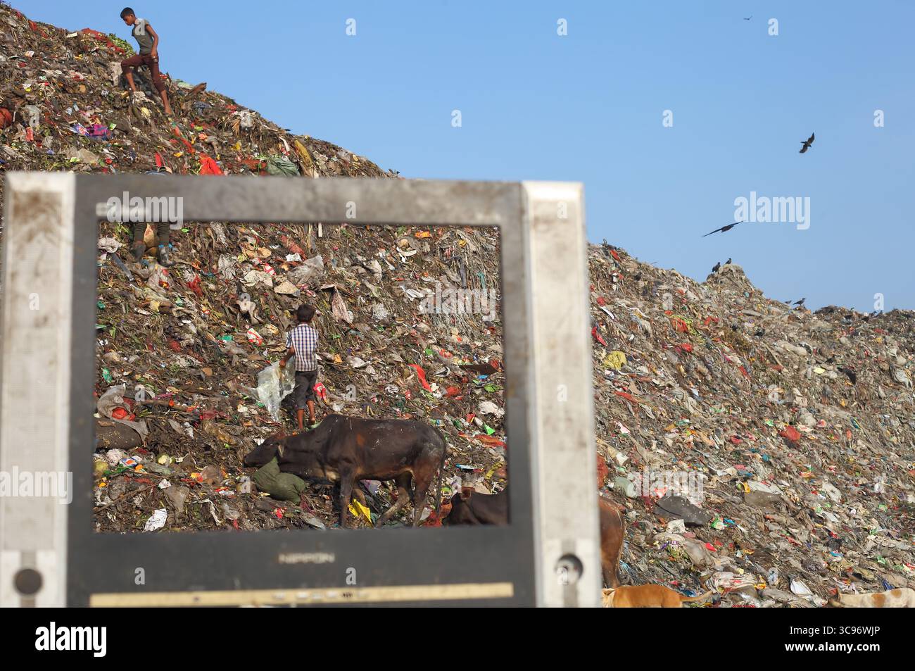 Chittagong, Bangladesh - 15 novembre 2018: Veduta di una vasta discarica dove gli scavatori cercano materiali riciclabili tra i torreggianti cumuli di rifiuti sotto un cielo luminoso. Foto Stock