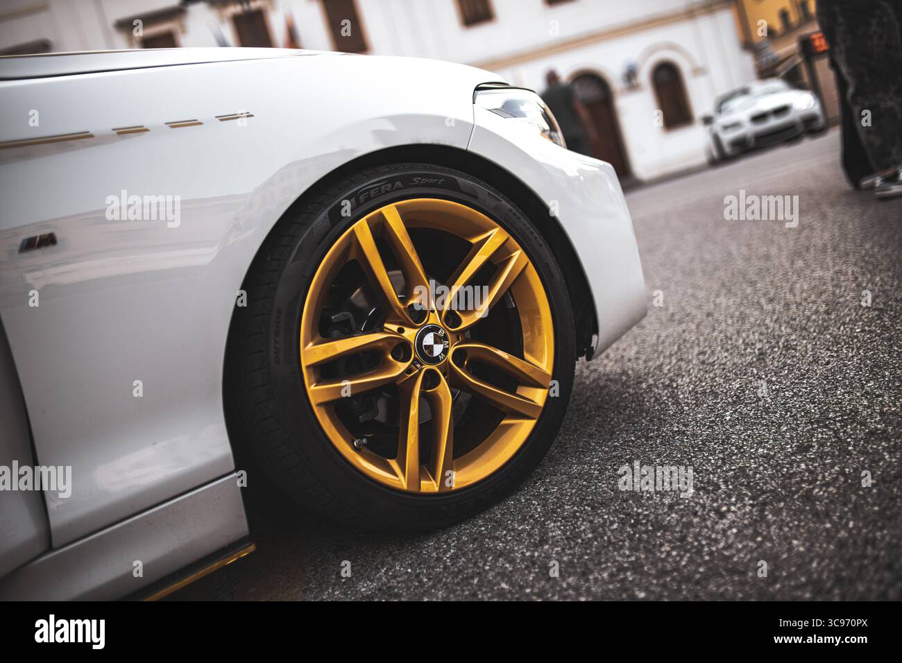 Roma, italia 5 agosto 2025: Cerchio dorato e pneumatico a profilo basso di un'auto sportiva di colore bianco parcheggiata su asfalto Foto Stock