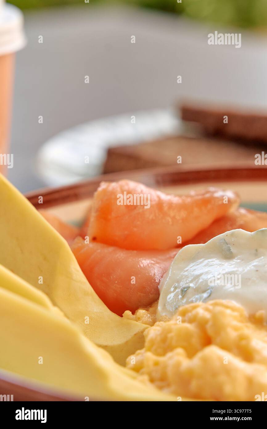 Un delizioso piatto da colazione con uova strapazzate, salmone fresco e salsa cremosa, perfetto per un'esperienza gourmet Foto Stock