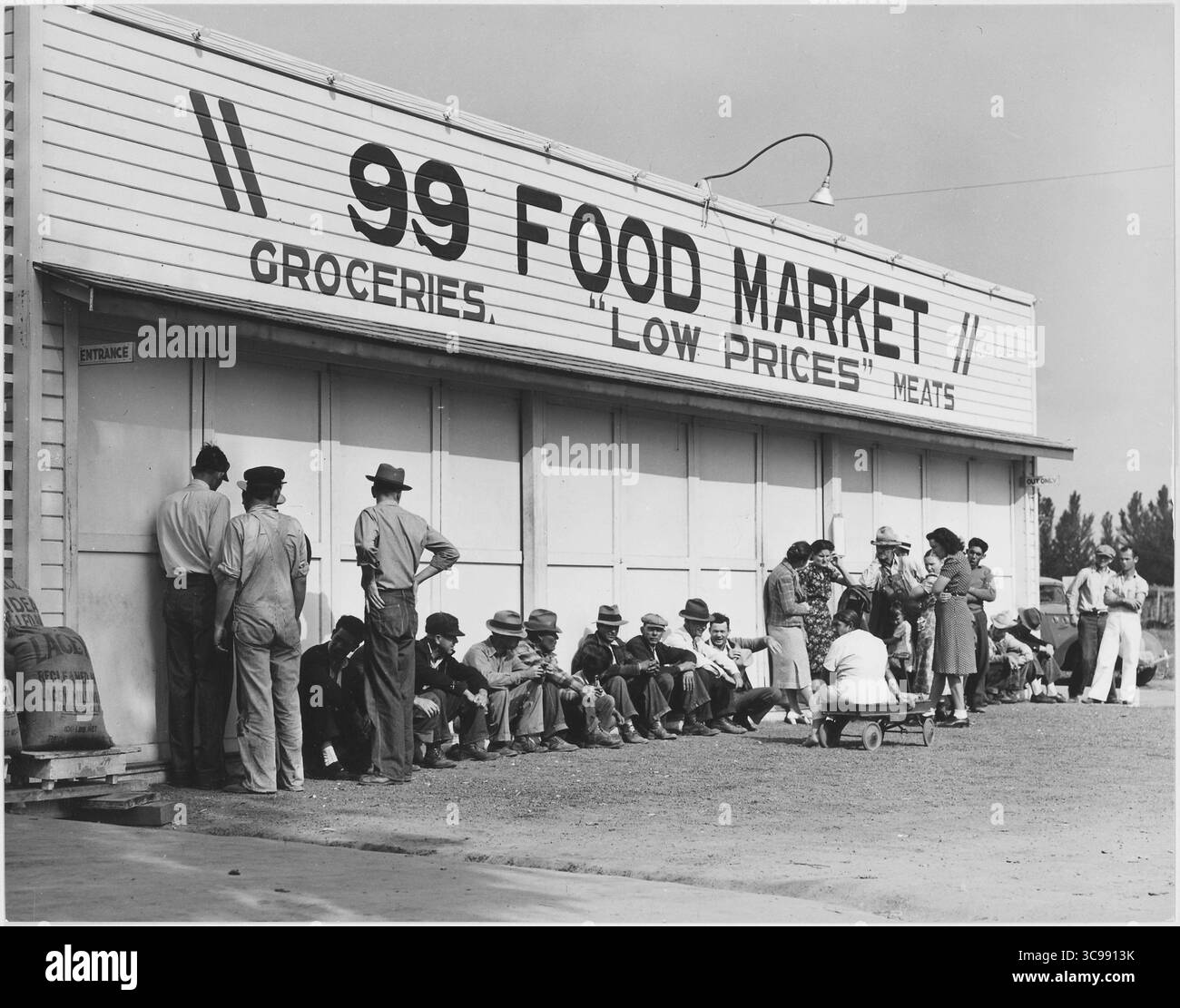 1,5 km circa a sud di Tulare, Tulare County, California. Line up di clienti di soccorso, la mattina presto, fuori dal negozio di alimentari dove verrà effettuata la distribuzione federale di commoditite eccedentarie. In questo giorno riceveranno zucchero, arance, mele, fagioli secchi. Tulare è una città agricola. Foto Stock