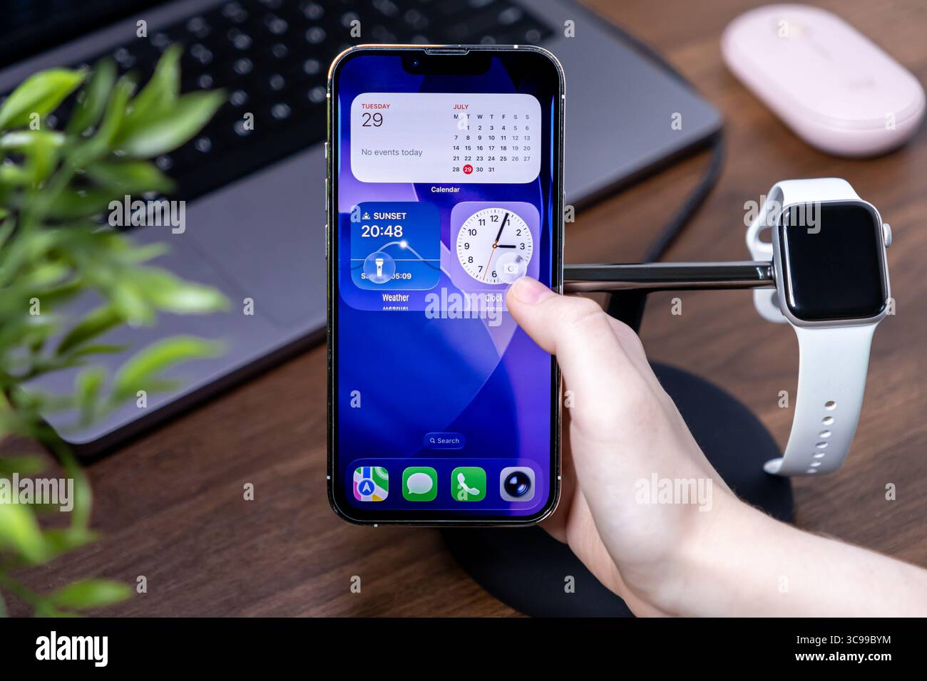 Poznan, Polonia - 29 luglio 2025: Una mano interagisce con gli intuitivi widget in vetro liquido ios 26 dell'iPhone, evidenziando l'integrazione dei moderni dispositivi intelligenti Foto Stock