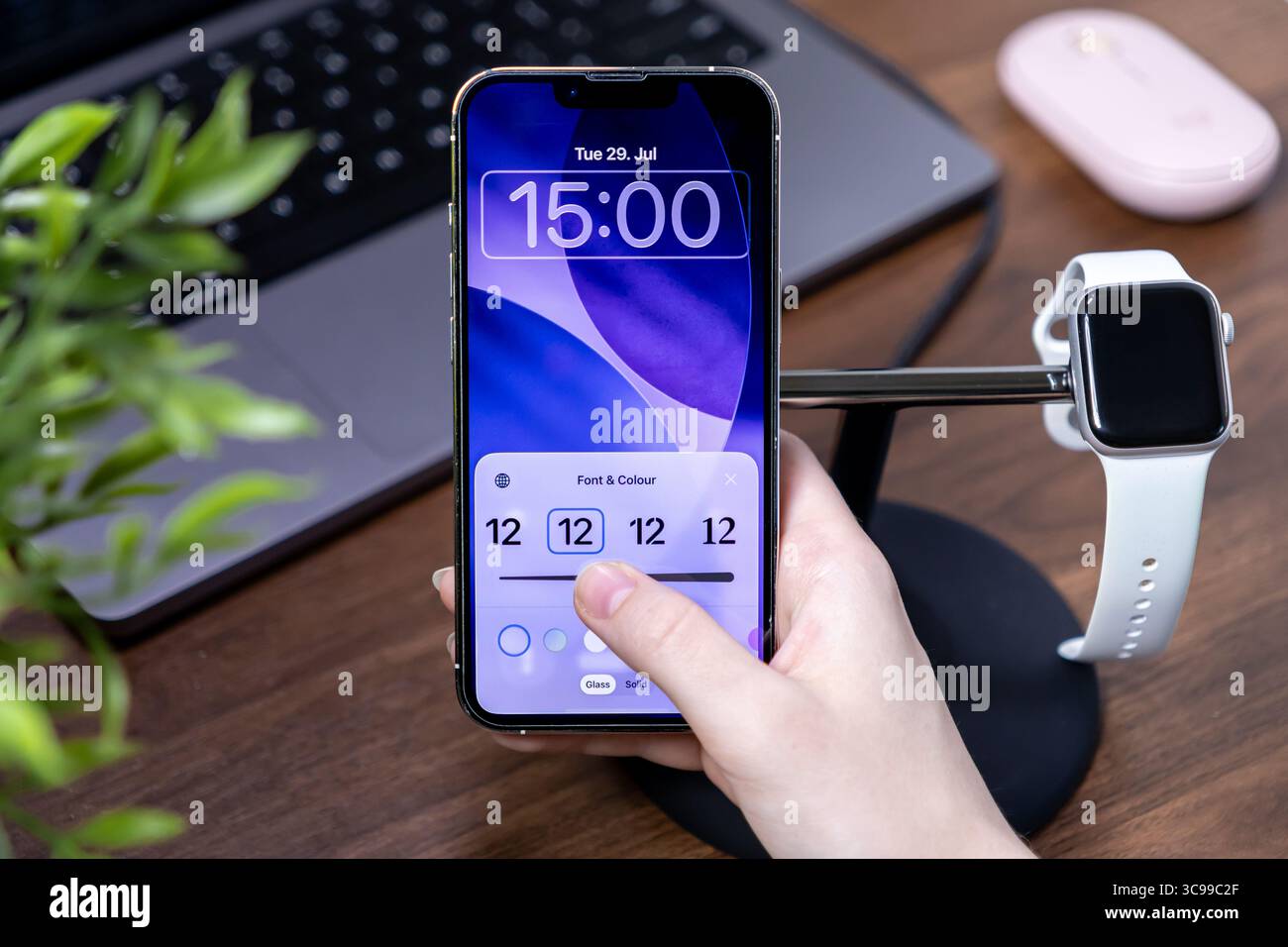 Poznan, Polonia - 29 luglio 2025: Hand personalizza la schermata di blocco iPhone Apple ios 26, regolando il carattere e il colore del vetro liquido per un design mobile personalizzato Foto Stock