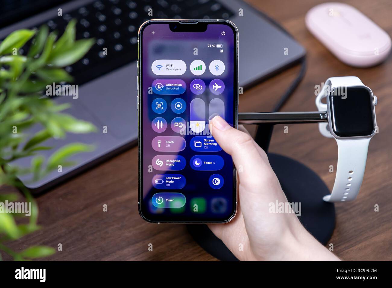 Poznan, Polonia - 29 luglio 2025: Una mano manipola i controlli digitali su uno smartphone, con software ios 26 reattivo e un vivace display Liquid Glass Foto Stock