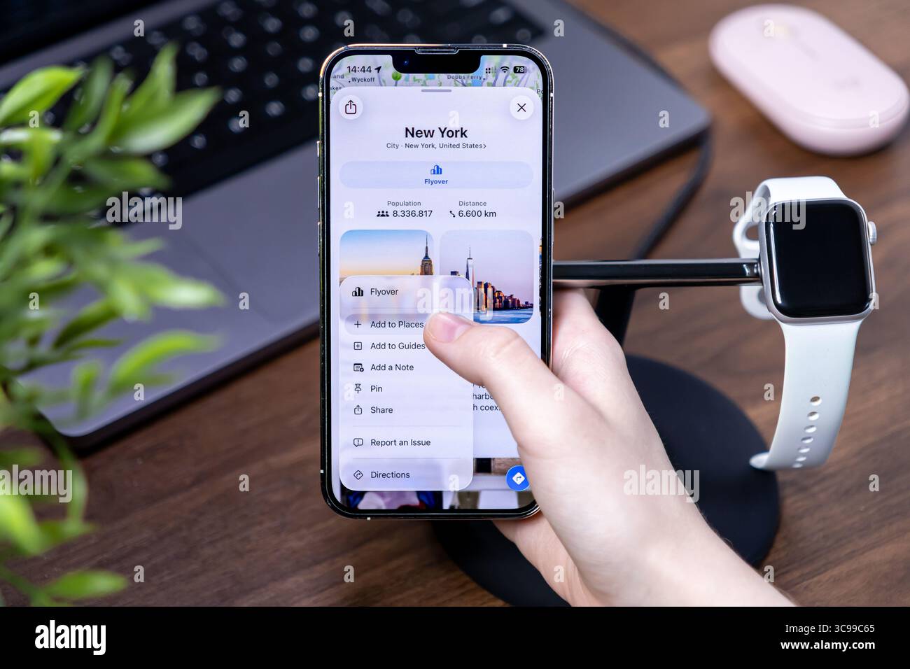 Poznan, Polonia - 29 luglio 2025: Apple Maps, con ios 26 e Liquid Glass, mostra le informazioni di New York su un iPhone, la mano dell'utente che interagisce, riflettendo il moderno Foto Stock