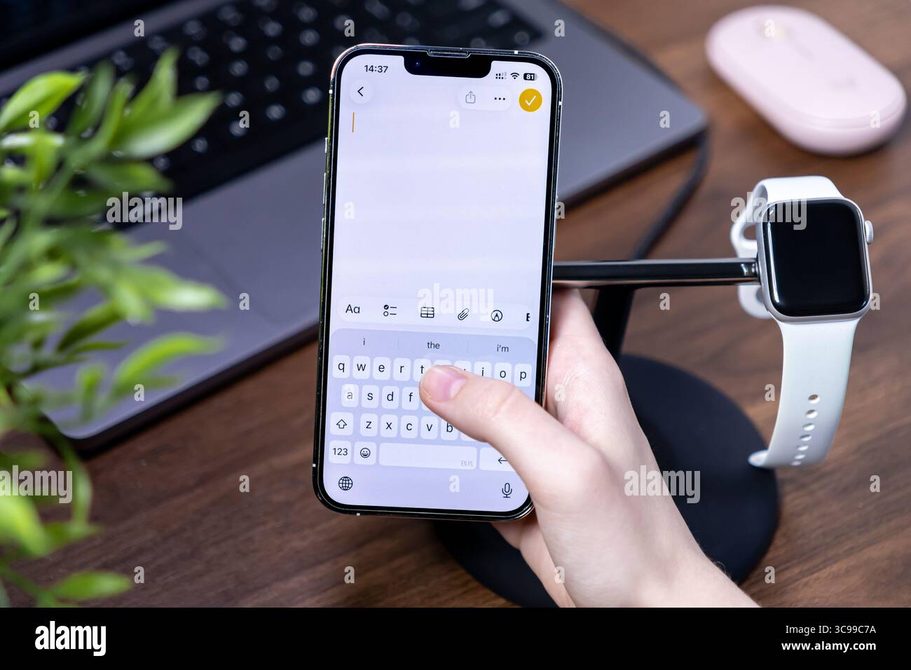 Poznan, Polonia - 29 luglio 2025: Una mano interagisce con uno smartphone, mostrando il sulla sua moderna tastiera, costruita con ios 26 e Liquid Glass avanzati Foto Stock