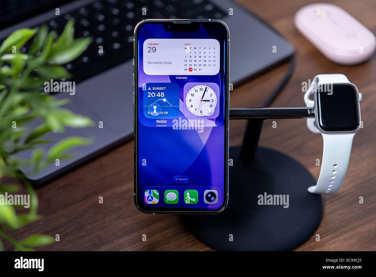 Poznan, Polonia - 29 luglio 2025: IPhone Apple, con widget ios 26 e display in vetro liquido, su un supporto di ricarica con Apple Watch, Highlightin Foto Stock