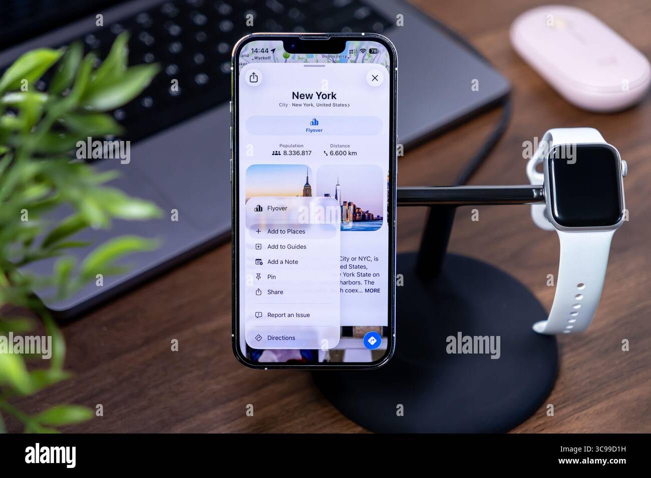 Poznan, Polonia - 29 luglio 2025: Uno schermo Apple iPhone mostra i dati di New York, con ios 26 e Liquid Glass, accanto ad Apple Watch, per la sinergia dei dispositivi Foto Stock