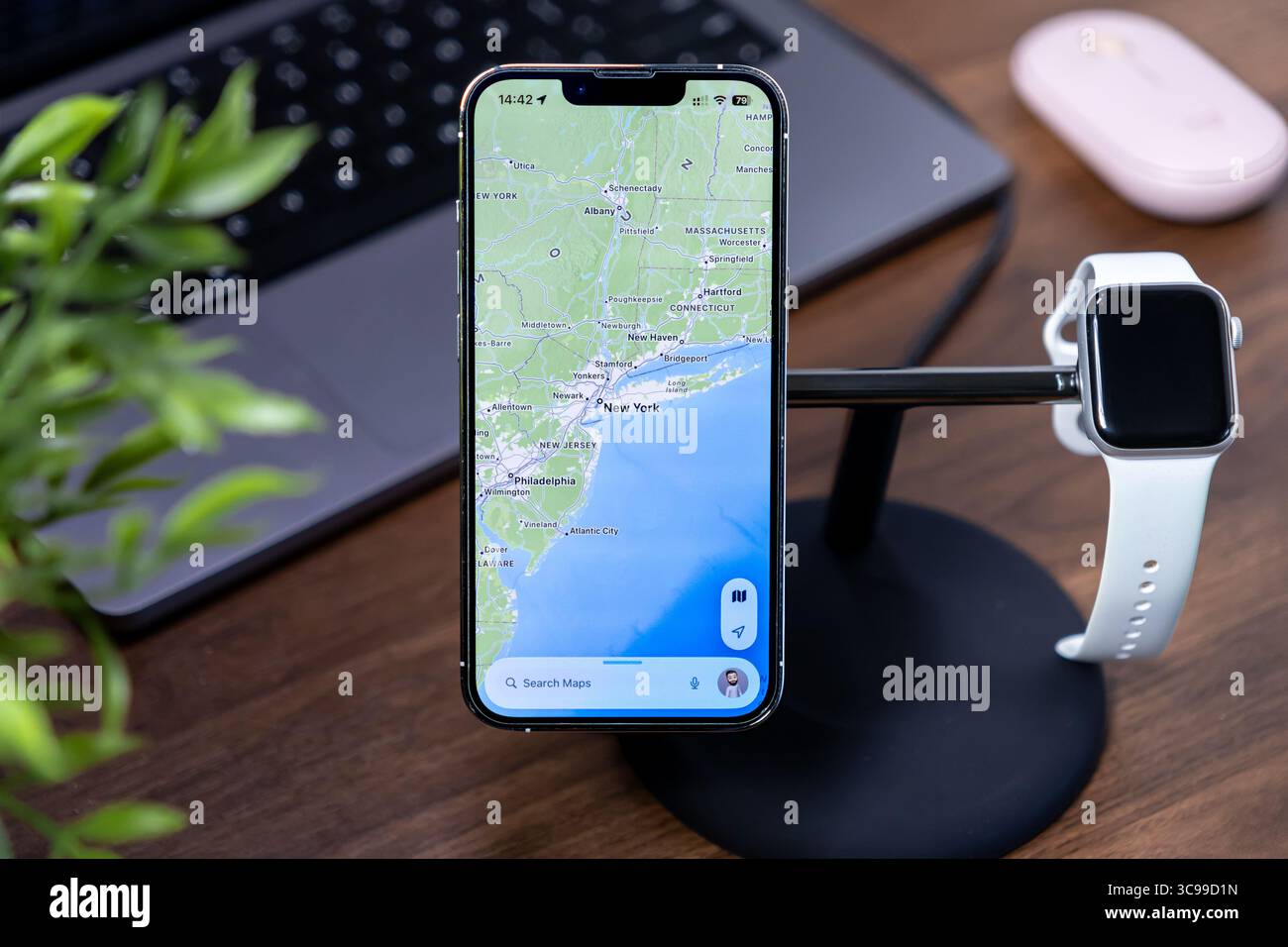 Poznan, Polonia - 29 luglio 2025: Smartphone moderno con mappa di New York, ios 26, vetro liquido, su supporto da scrivania, accanto all'orologio, pianificazione digitale dei viaggi Foto Stock