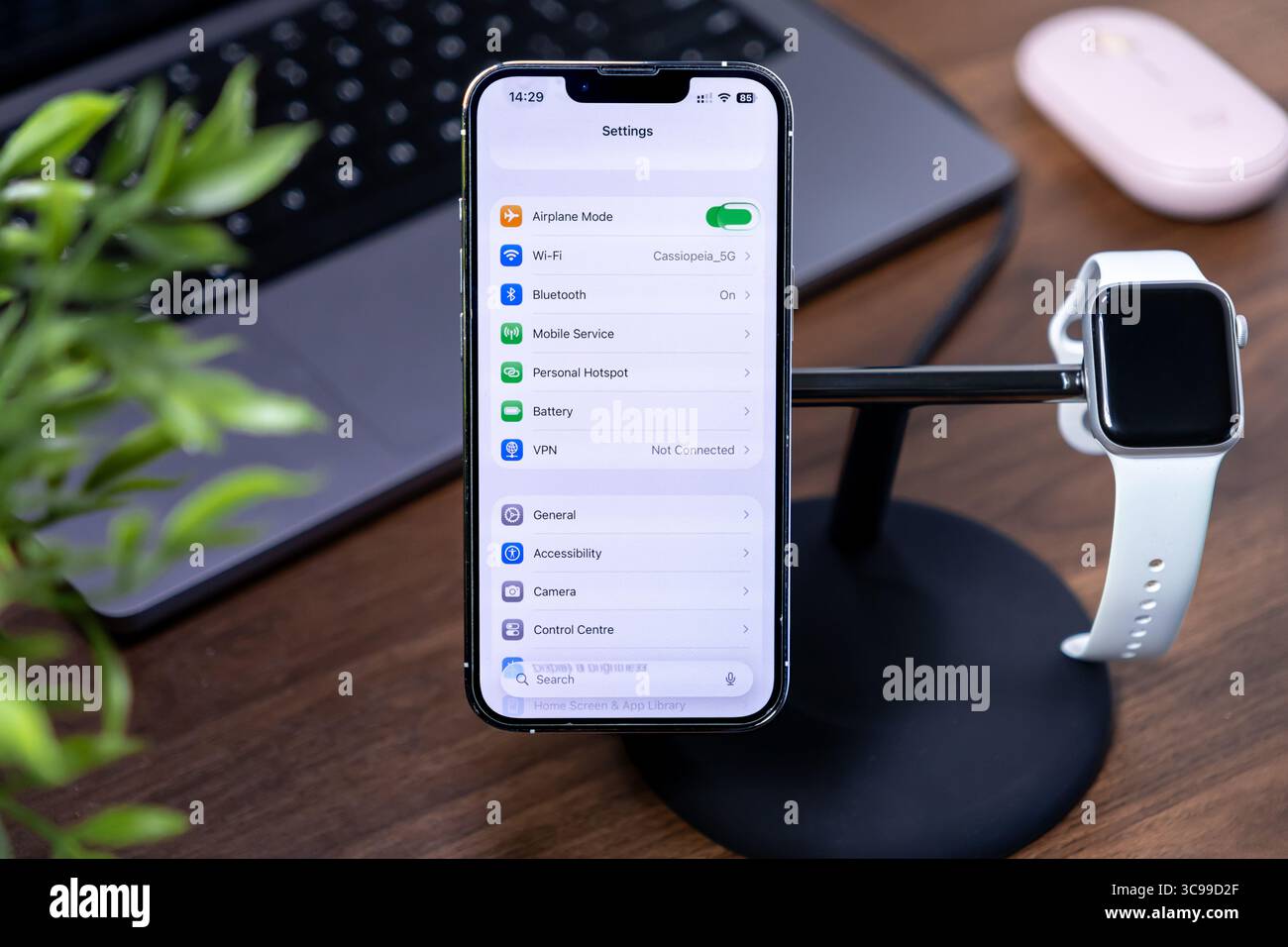 Poznan, Polonia - 29 luglio 2025: Un iPhone e un Apple Watch su un supporto di ricarica da tavolo, che rappresenta ios 26 e Liquid Glass per la moderna truffa dei dispositivi digitali Foto Stock