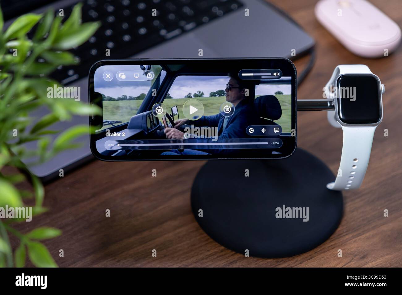 Poznan, Polonia - 29 luglio 2025: Uno smartphone che visualizza i contenuti multimediali su un elegante supporto da scrivania con un orologio intelligente, basato su ios 26 e tecnologia Liquid Glass Foto Stock