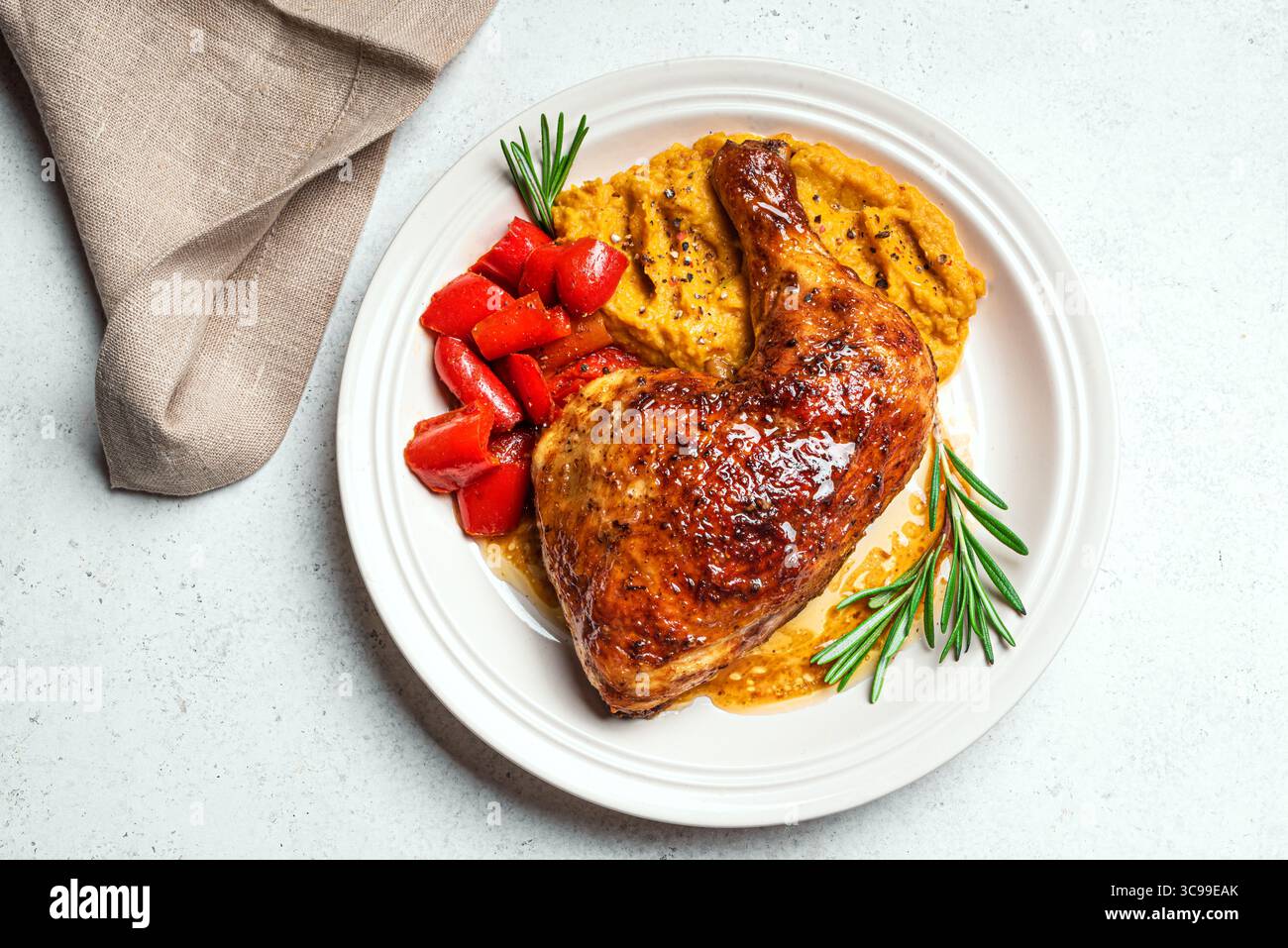 Pasto autunnale: Quarto di pollo glassato al miele arrosto con purè di zucca, paprika al forno, sugo di carne e rosmarino su sfondo bianco, vista dall'alto, spazio per copiare. Se Foto Stock