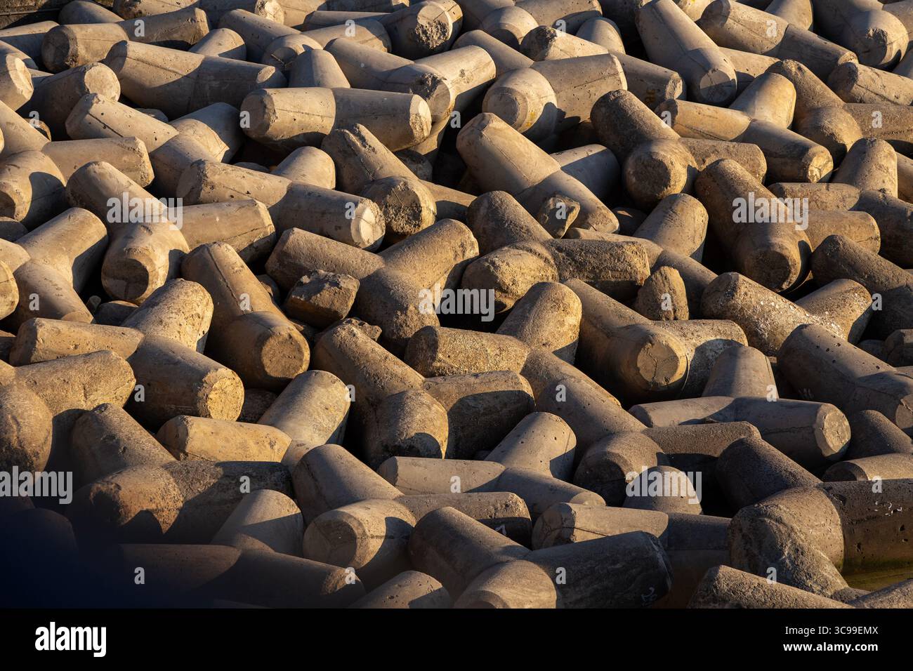 Grandi tetrapodi in cemento ammassati lungo la costa, utilizzati come demolitori per proteggere la costa, formando una struttura geometrica e testurizzata unica Foto Stock