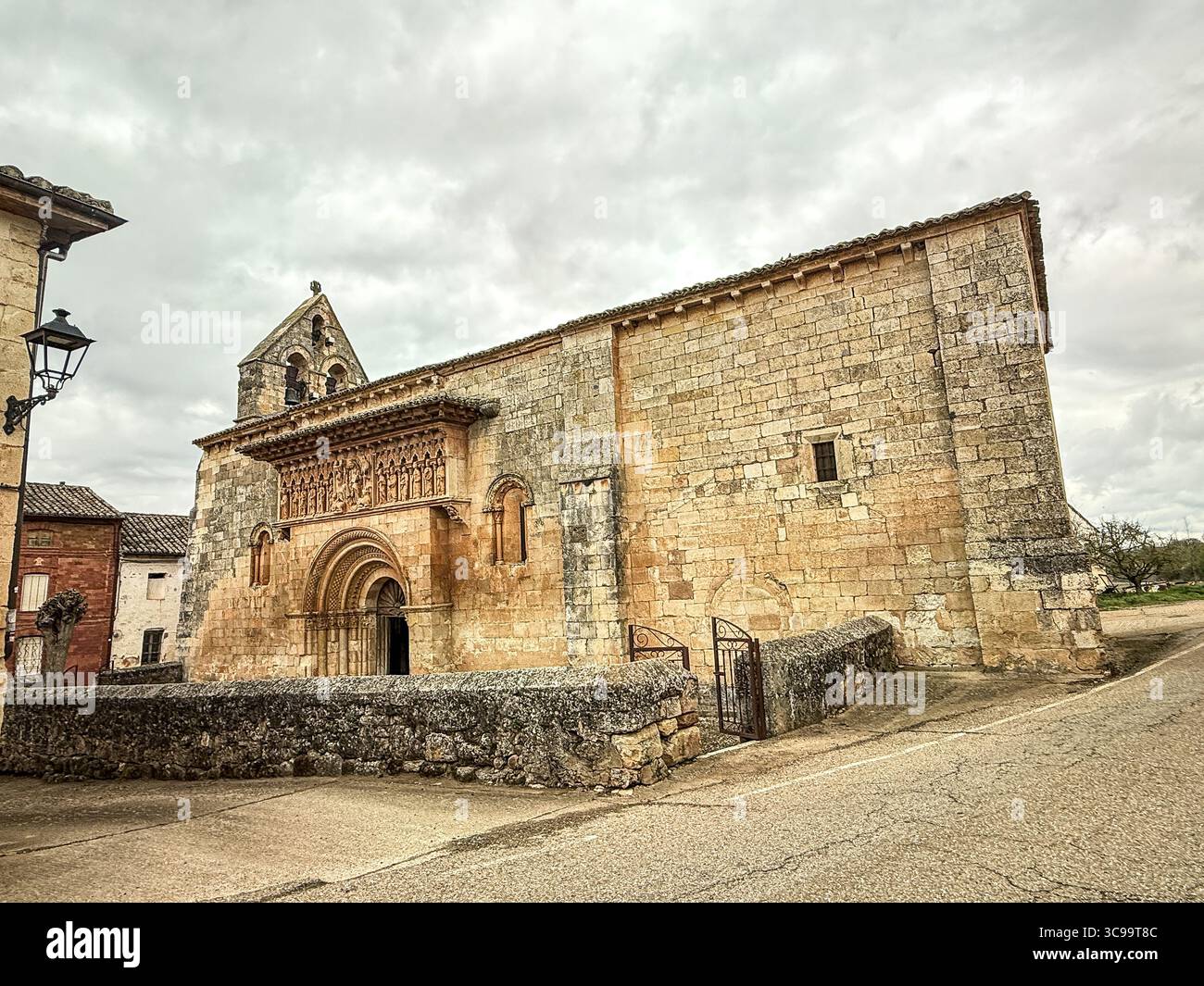 Storica chiesa romanica con portale decorato scolpito, campanile in pietra e robuste pareti in muratura. Foto Stock