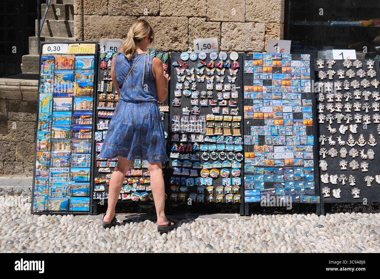 Una donna sfoglia souvenir in un negozio turistico nella città vecchia di Rodi, in Grecia Foto Stock