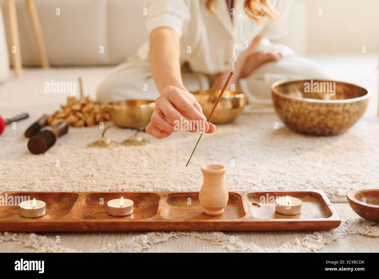 Bastoncino di incenso per l'illuminazione manuale femminile per meditazione, consapevolezza e relax in un accogliente ambiente di benessere domestico Foto Stock