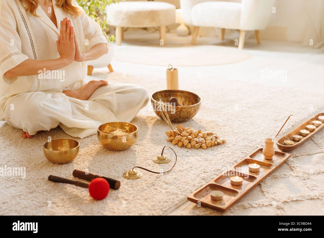 Meditazione tranquilla in casa con donna a Namaste posa circondato da candele che cantano ciotole incenso per la consapevolezza spirituale e il relax benessere Foto Stock