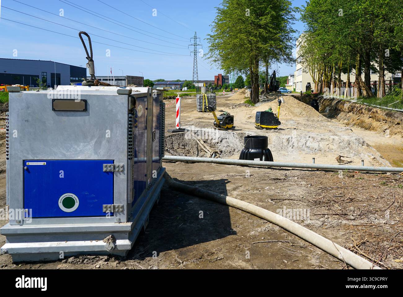 Cantiere con unità pompa di drenaggio in funzione durante i lavori terrestri in una giornata di sole Foto Stock