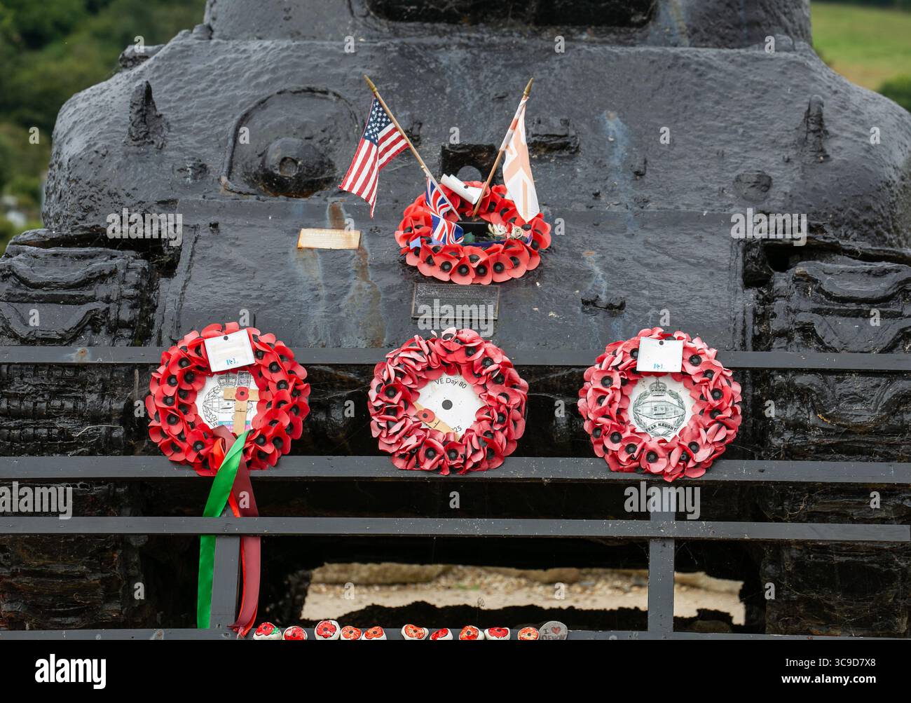 Uno storico carro armato militare Sherman adornato da corone di papavero e bandiere che commemorano i soldati caduti in un ambiente commemorativo Slapton Sands Devon Foto Stock