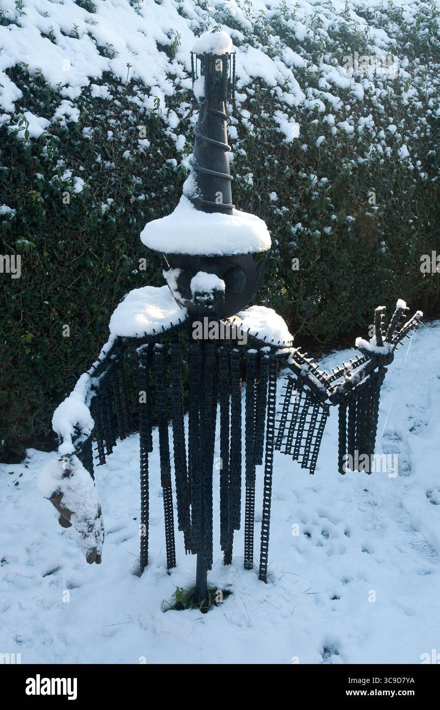 Coperte di neve una scultura creativa in giardino, che crea un'atmosfera stravagante in un cortile residenziale in una luminosa giornata invernale. Foto Stock