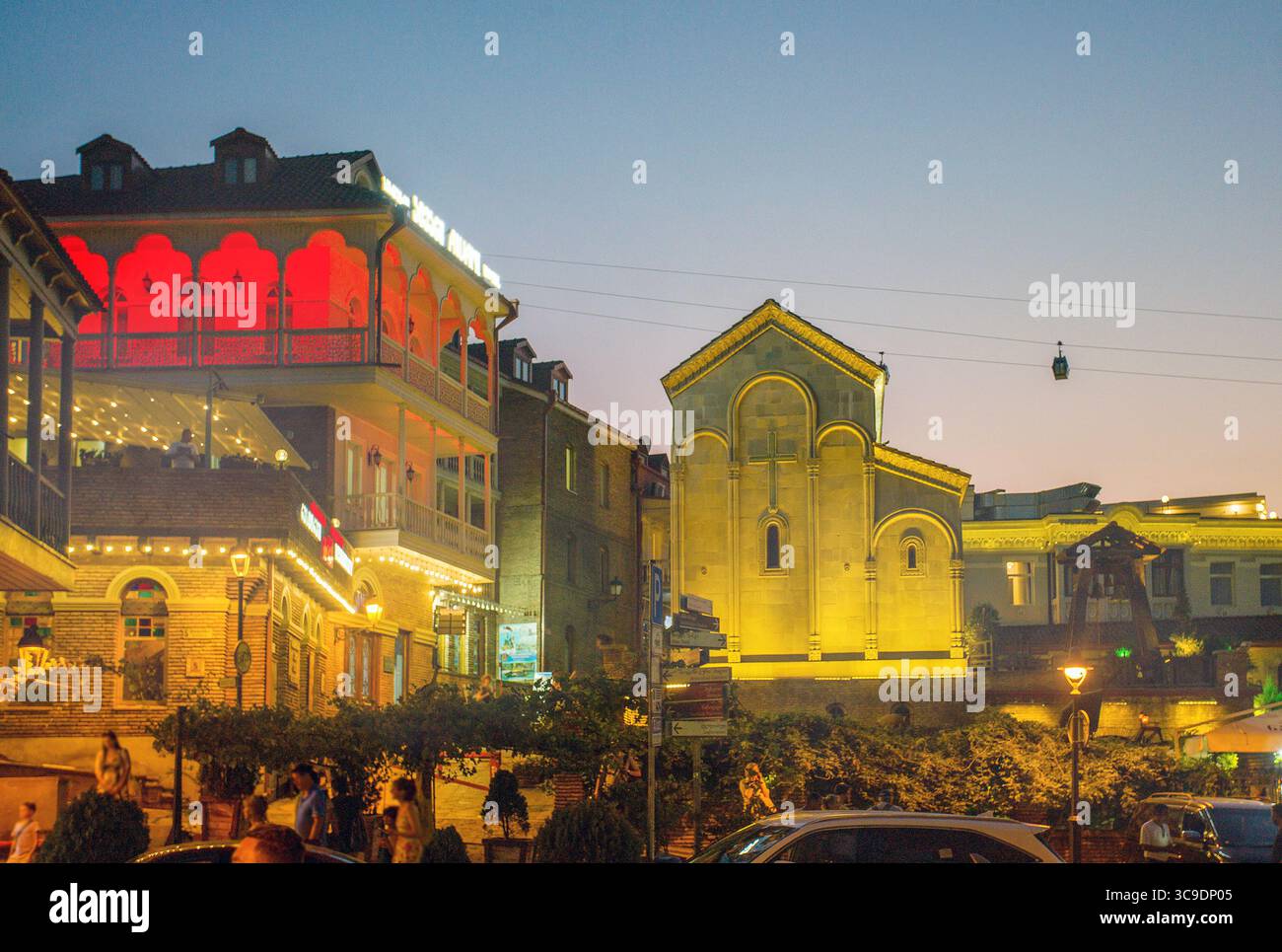 Centro e città vecchia di Tbilisi, cabinovia in aria con luci al crepuscolo della città illuminata - ora metà estate - caldo ma gente che appare sulle strade - vista f Foto Stock