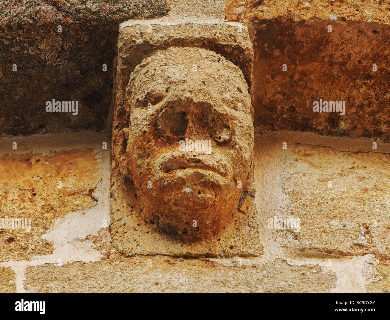 Una vista dettagliata di una testa di pietra intemprata sull'eremo romanico di Calatañazor, che riflette l'arte ornamentale medievale. Foto Stock