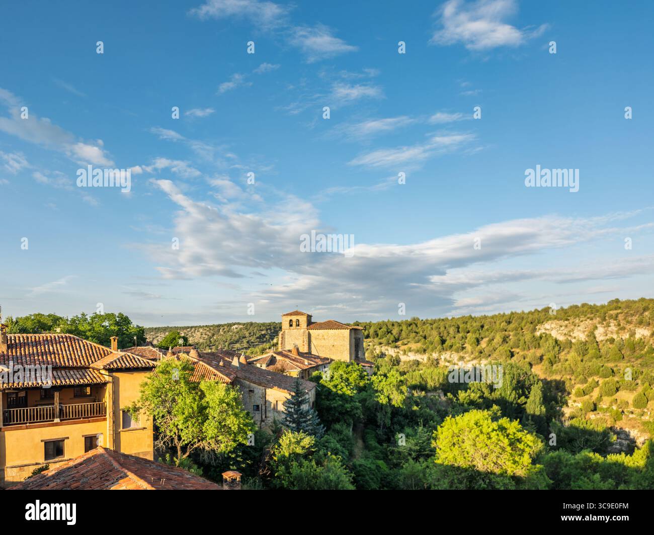 Calatañazor rivela i suoi affascinanti tetti in terracotta annidati tra gli alberi, con un campanile che segna lo storico villaggio di Castilla y Leon. Foto Stock