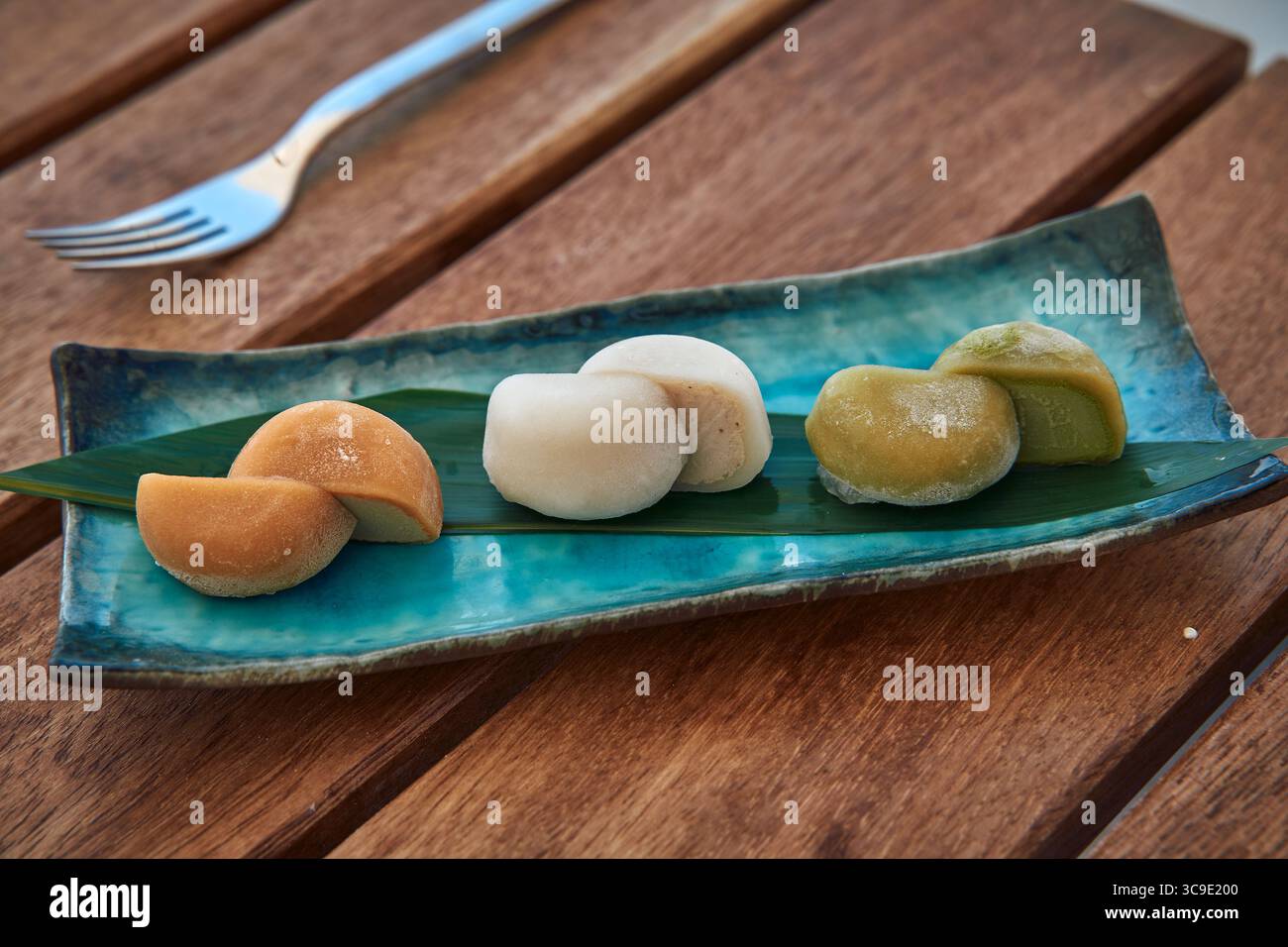 Una deliziosa presentazione di tre varietà di delizia Mochi su un bellissimo piatto circondato da elementi naturali, ideale per gli amanti dei dolci e la Culina Foto Stock