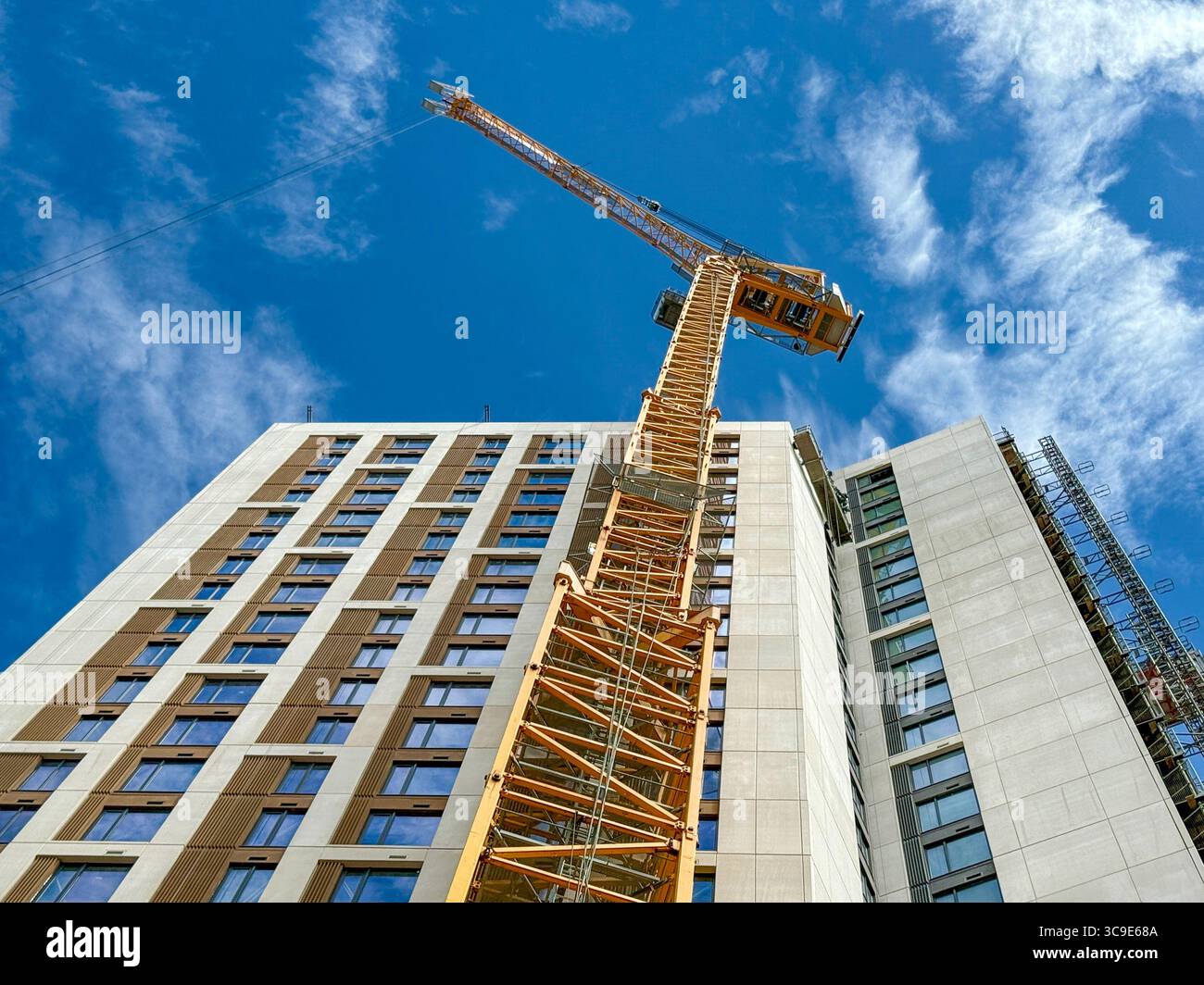 Cardiff, Galles, Regno Unito - 16 luglio 2025: Vista ad angolo basso che guarda su una gru a torre alta all'esterno di un nuovo blocco di appartamenti nel centro di Cardiff. - Immagine stock catturata con smartphone