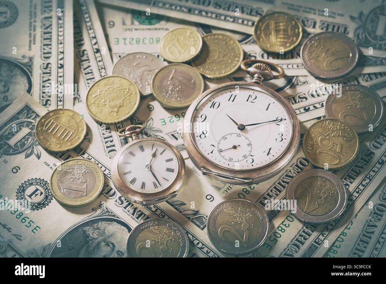 Il tempo è un concetto di finanza monetaria con vecchi orologi d'epoca, banconote in dollari e monete in euro. Immagine tonificata. Foto Stock