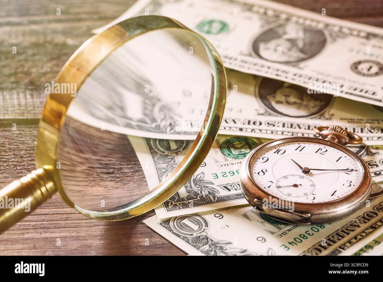Il tempo è un concetto di finanza con vecchi orologi vintage, banconote da un dollaro e lente d'ingrandimento su un tavolo in legno. Foto Stock