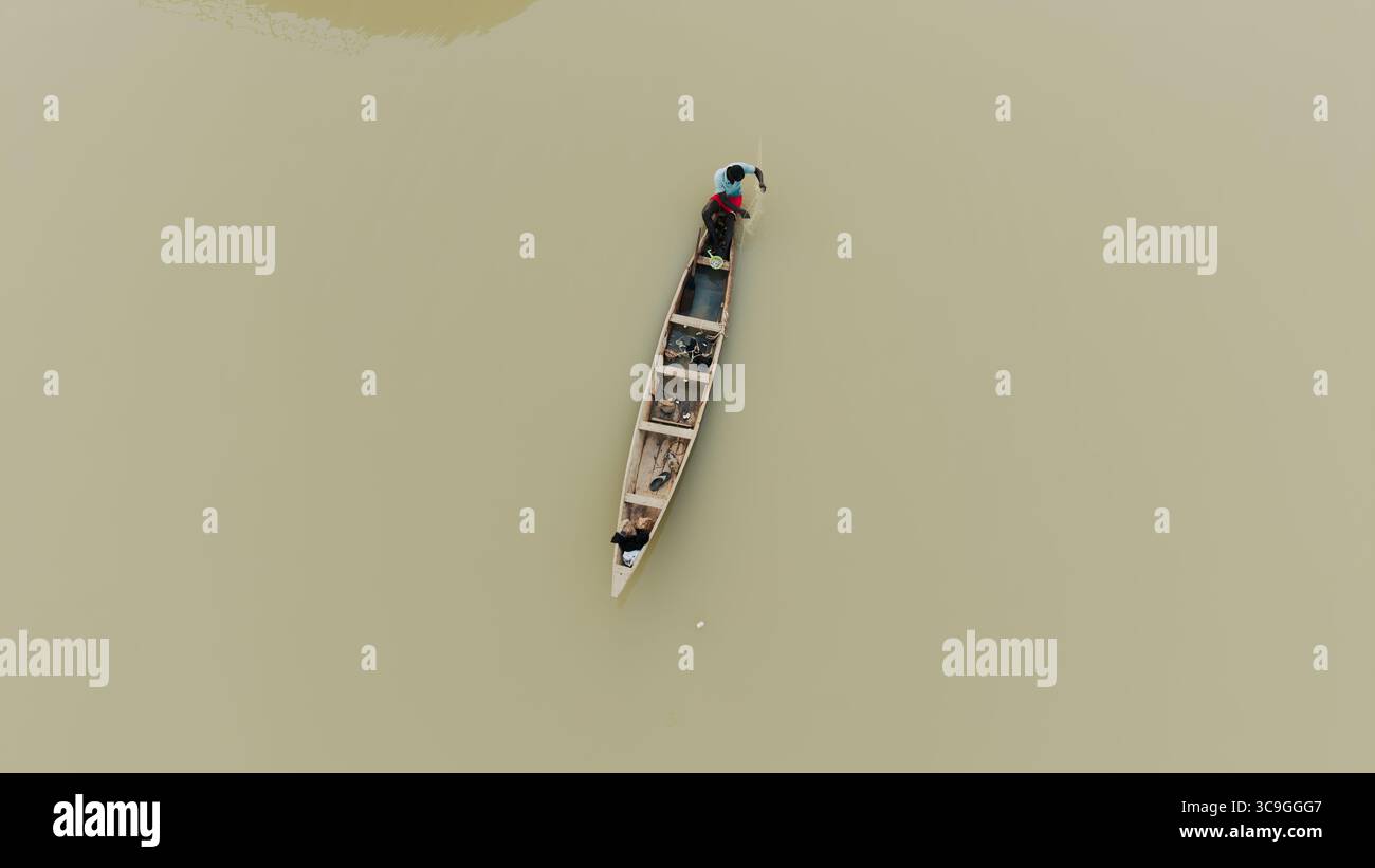Vista aerea di una piccola barca di legno che affonda le acque torbide, con gli occupanti a bordo, Rimi, Katsina, Nigeria. Foto Stock