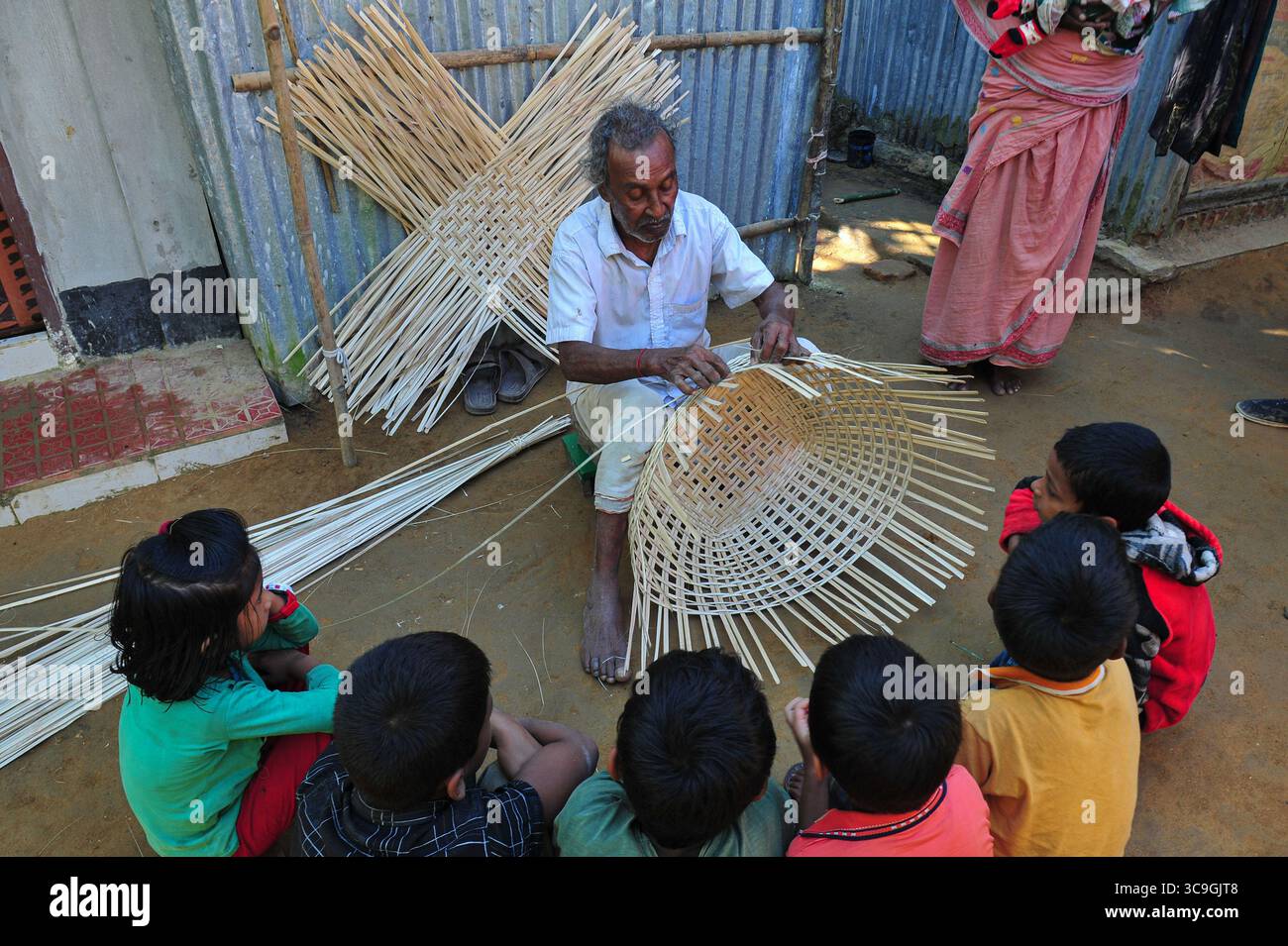 25 novembre 2022: 26 novembre 2022. Sylhet, Bangladesh: Moyna Biswas 80 anni, un'artista artigianale di canna da zucchero di Haripur, nell'area di Sylhet, sta tessendo un prodotto di canna mentre i suoi eredi stanno osservando e imparando accanto a lui. Egli è certo che il suo erede non prenderà questo lavoro artigianale di canna da zucchero come professione, mentre i prodotti di plastica sono disponibili sul mercato a un prezzo inferiore a quello della canna da zucchero e peggiorano già il mercato. (Immagine di credito: © MD Rafayat Haque Khan/ZUMA Press Wire) Foto Stock