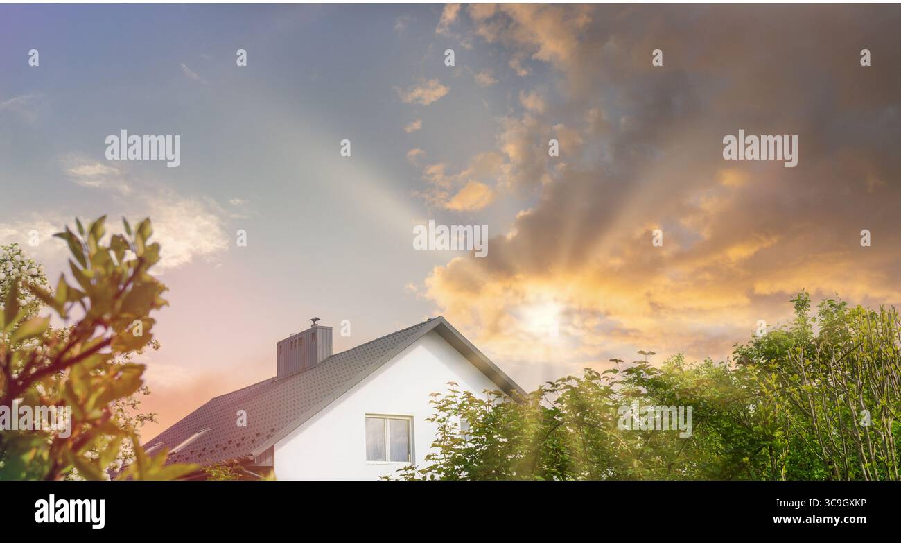Una casa affascinante immersa nel verde cattura l'essenza della sostenibilità. Il cielo è dipinto con colori caldi mentre il sole tramonta, evidenziando reso Foto Stock