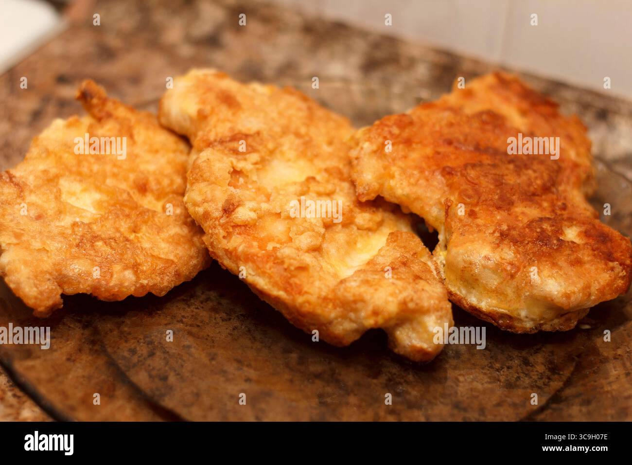 Cotolette di pollo fritte dorate impilate su un piatto. Consistenza croccante e aspetto appetitoso. Ideale per temi legati al cibo e presentazioni culinarie Foto Stock