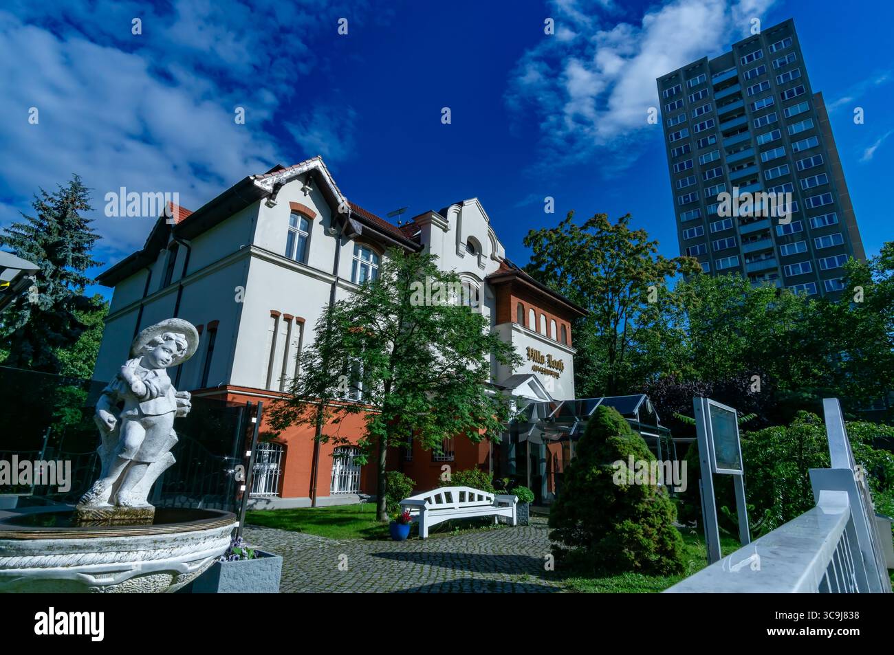 La storica Villa Looß di Berlino contrasta con un tipico grattacielo della Germania Est nel quartiere Fennpfuhl in una soleggiata giornata estiva. Foto Stock