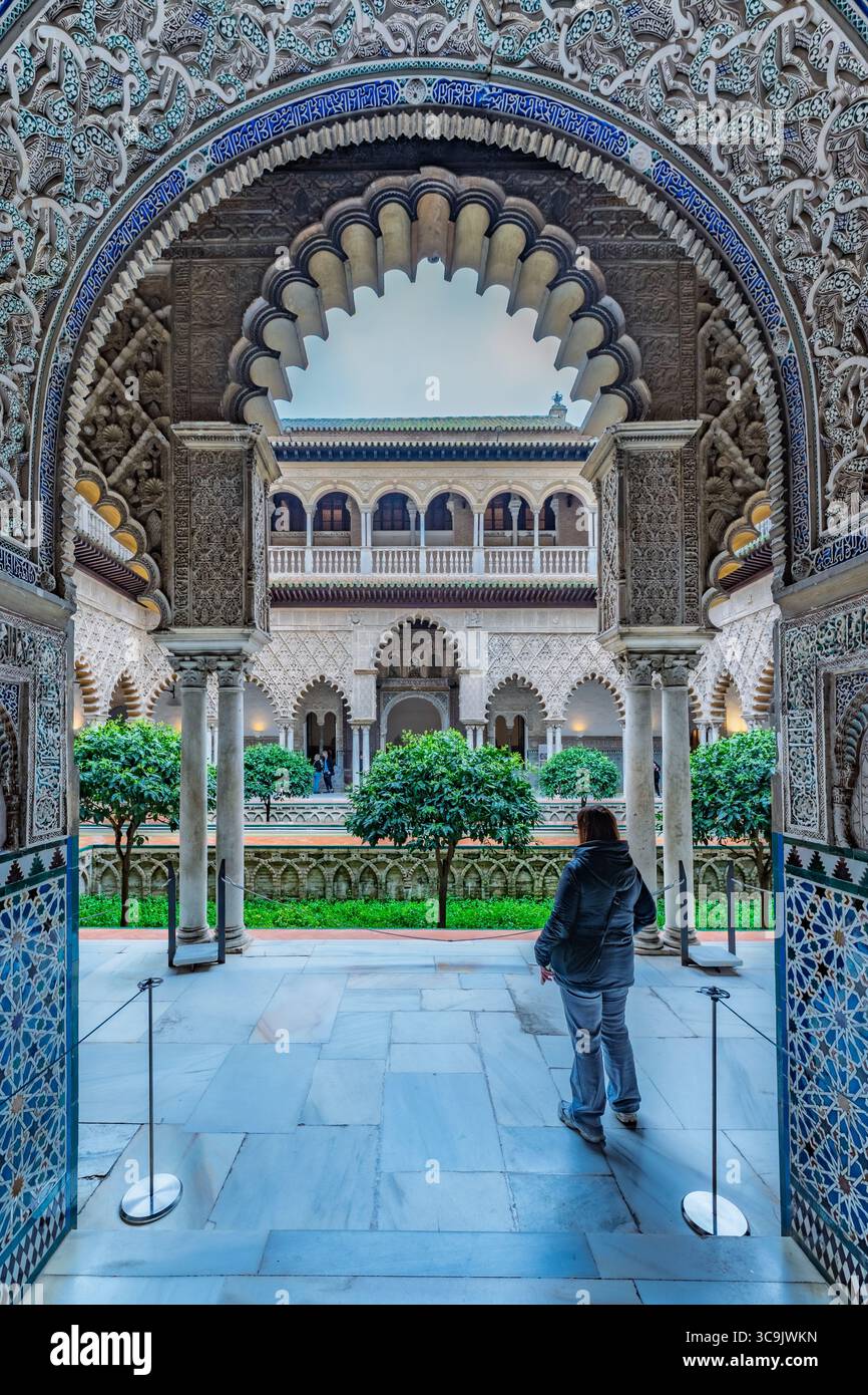 Un'arcata decorata incornicia un tranquillo cortile nel Real Alcazar. Il palazzo reale, un sito patrimonio dell'umanità dell'UNESCO, presenta una maestosa architettura moresca. Foto Stock