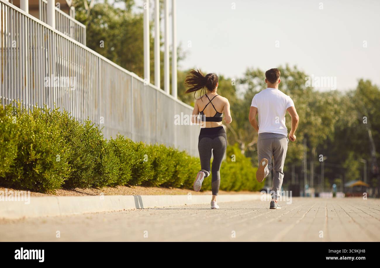 Vista posteriore di coppie sportive che indossano abbigliamento sportivo e che fanno jogging insieme nel parco. Foto Stock