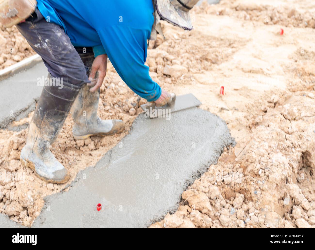 Il calcestruzzo magro viene rifinito con una cazzuola per garantire una superficie liscia e piana. Foto Stock