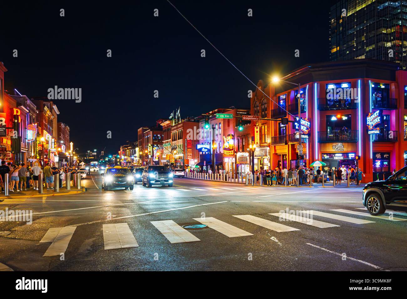 Vista notturna di Broadway Street illuminata, una delle principali attrazioni turistiche conosciuta per la sua vita notturna e la musica country dal vivo nel centro di Nashville, Tennessee. Foto Stock