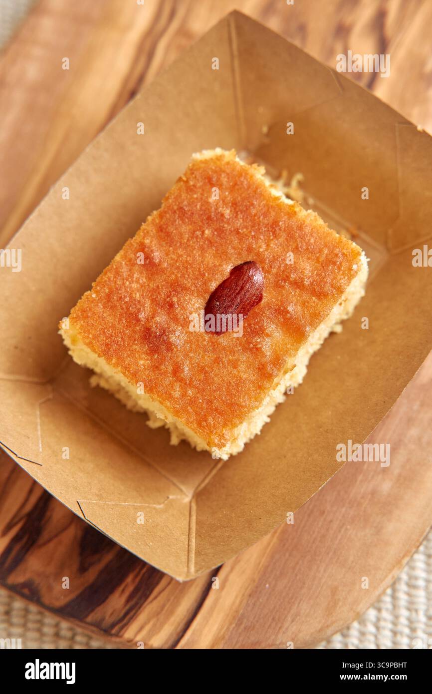 Deliziosa torta umida con contorno di mandorle servita su un piatto di carta rustica per un'esperienza dolce ad ogni boccone Foto Stock