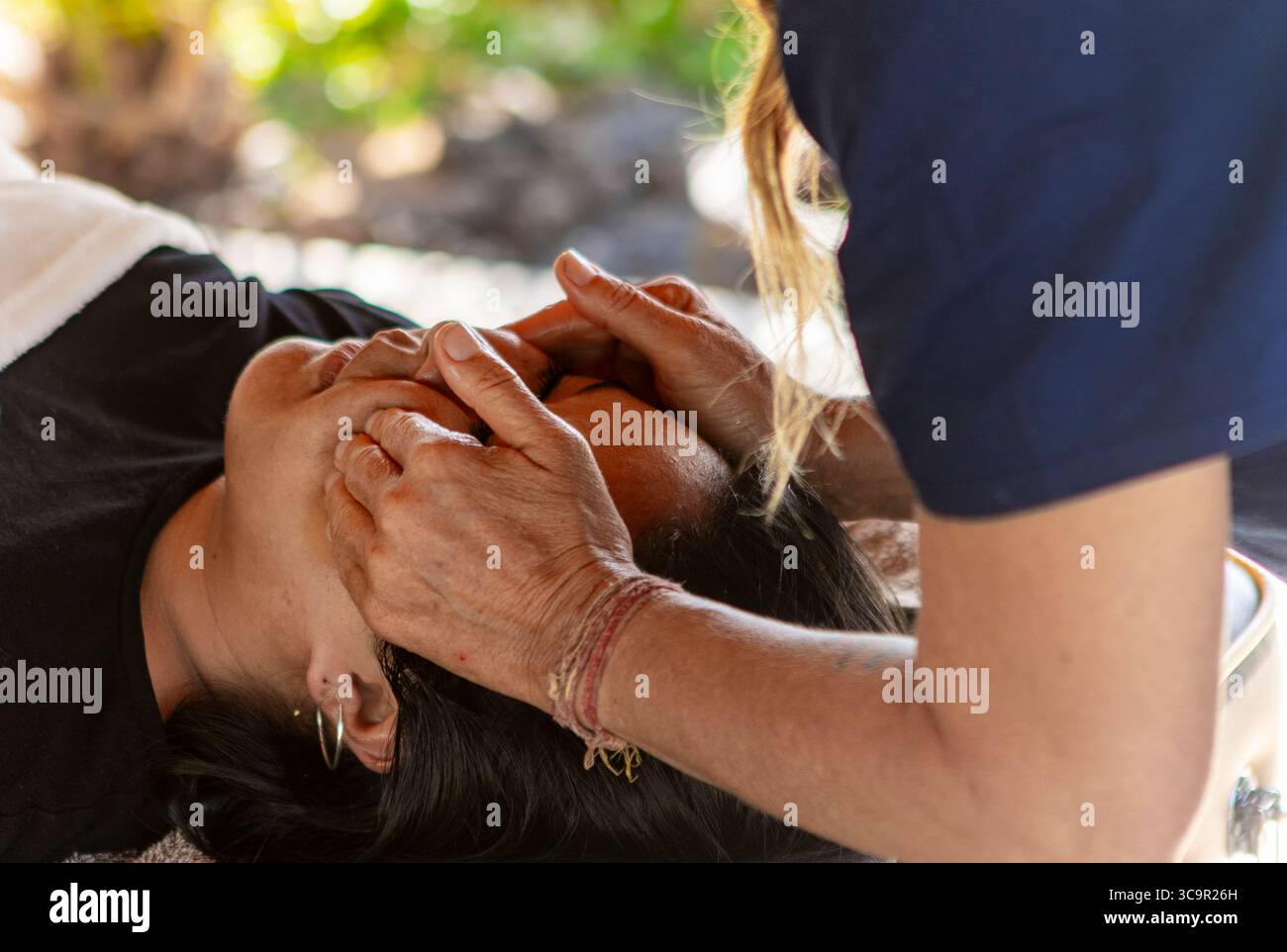 Donna che riceve un massaggio rilassante alla testa all'aperto, promuovendo la guarigione e una vita sana Foto Stock