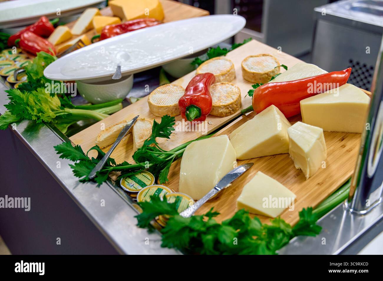 Un'accattivante esposizione di formaggi gourmet accompagnati da verdure fresche e cornici pronti per una delizia culinaria Foto Stock