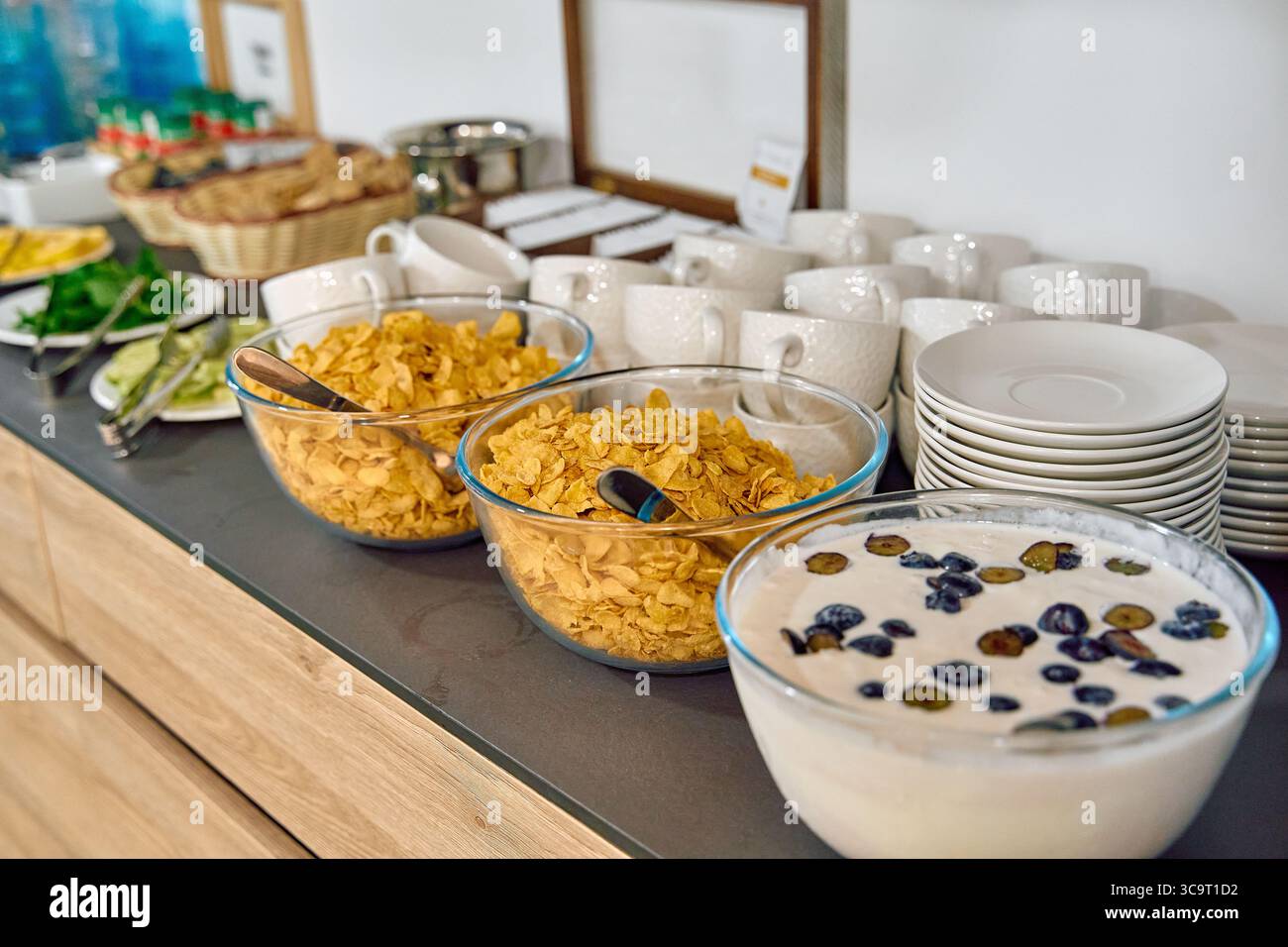 Un vivace buffet per la colazione con cereali croccanti, frutta fresca e cremoso yogurt circondato da eleganti stoviglie Foto Stock