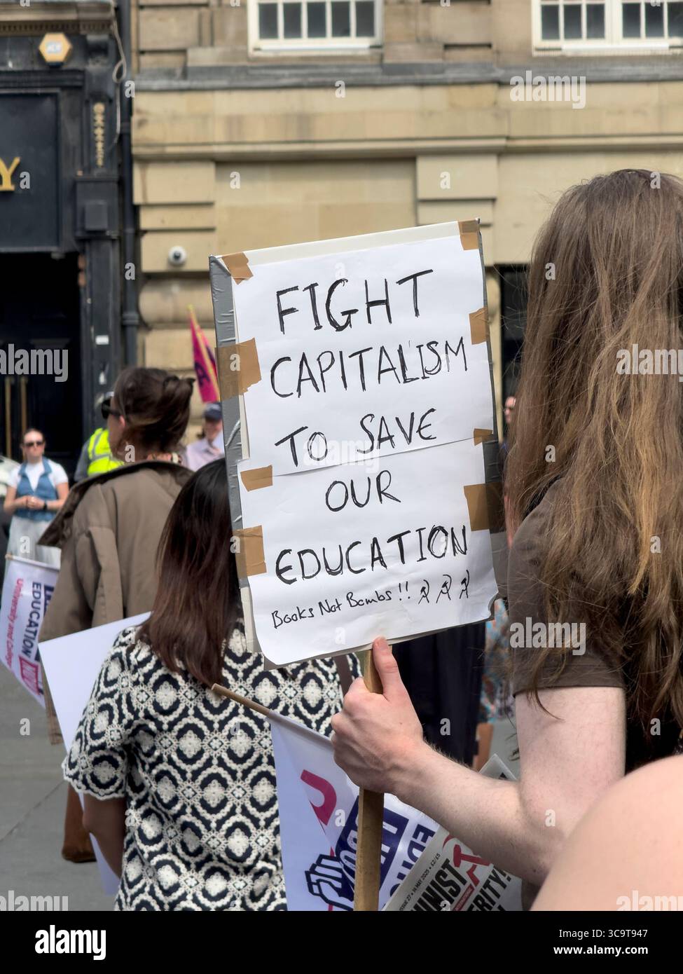 NEWCASTLE, TYNE AND WEAR, INGHILTERRA - 11 GIUGNO 2025: Protesta politica a Newcastle. Una donna sta in uno spazio pubblico con un cartello - Immagine stock catturata con smartphone
