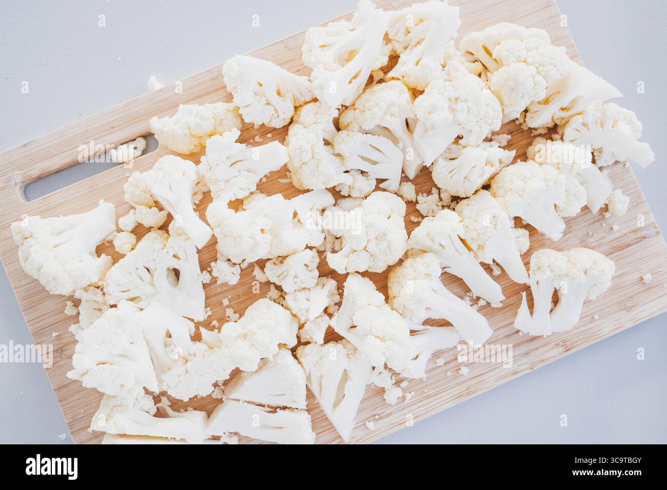cavolfiore fresco tritato su un tagliere rustico in legno, ricette salutari, preparazione dei pasti per il diabete e temi di cucina a base vegetale Foto Stock cavolfiore fresco tritato su un tagliere rustico in legno, ricette salutari, preparazione dei pasti per il diabete e temi di cucina a base vegetale Foto Stock