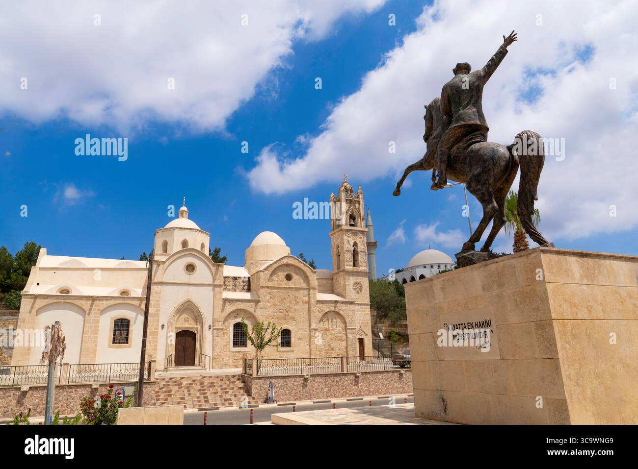 Dipkarpaz, Penisola di Karpas, Cipro del Nord - 14 luglio 2025: Statua di Ataturk a cavallo e vecchia Chiesa ortodossa di Ayios Synesios sullo sfondo Foto Stock