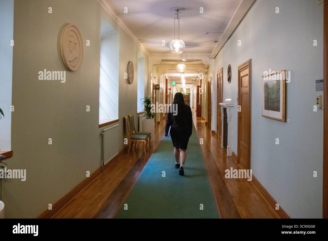 Stoccolma, Svezia - 10 luglio 2025: Una guida turistica femminile che cammina attraverso il corridoio del Parlamento svedese (Riksdagshuset), durante il quale i visitatori sono accompagnati Foto Stock