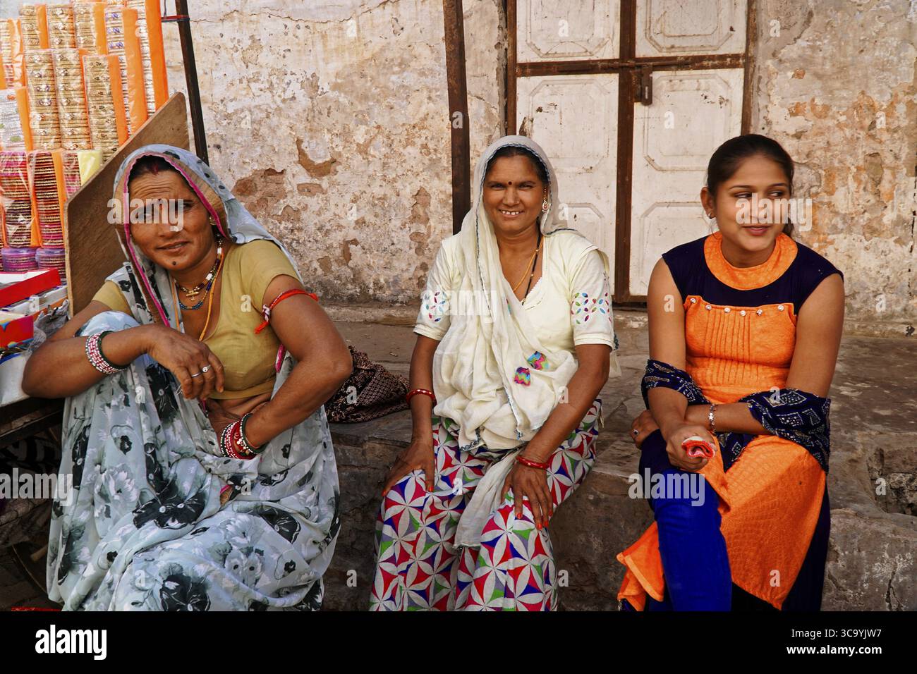 Jaipur, Rajasthan, India settentrionale, India, Asia, tre donne in abito tradizionale siedono sorridenti su una panchina in una strada indiana Foto Stock