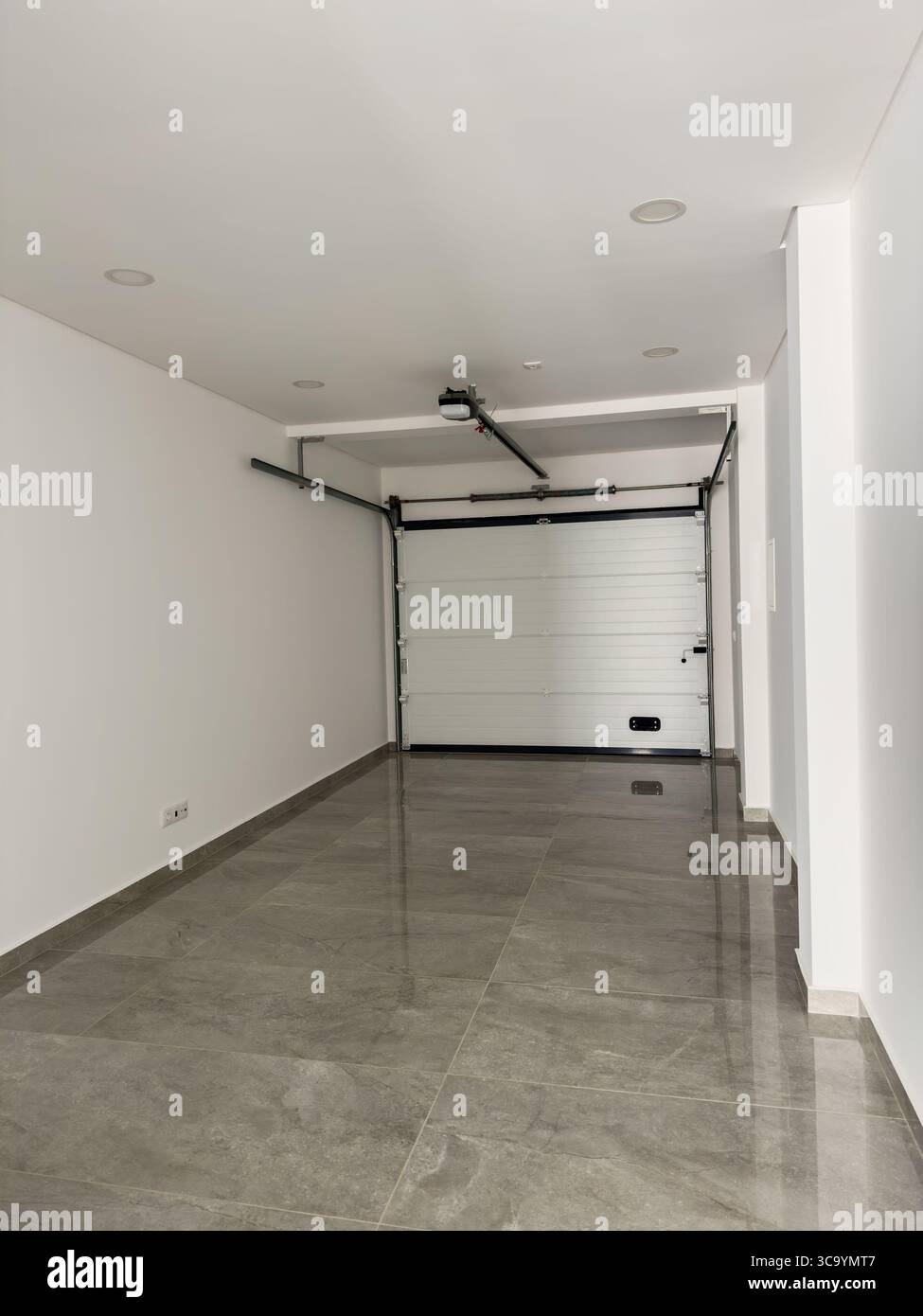 Garage pulito e spazioso con porta motorizzata e interni dal design elegante. Foto Stock